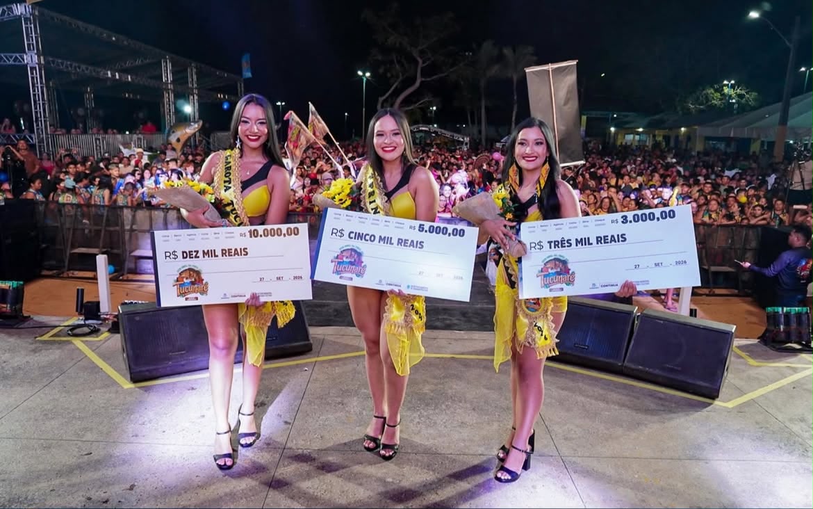 Vencedoras do concurso Garota Tucunaré 2026 sorridentes no palco, segurando cheques de premiação perante a multidão.